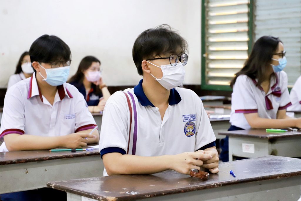 Nam học sinh mặc áo thun đồng phục ngồi trong lớp