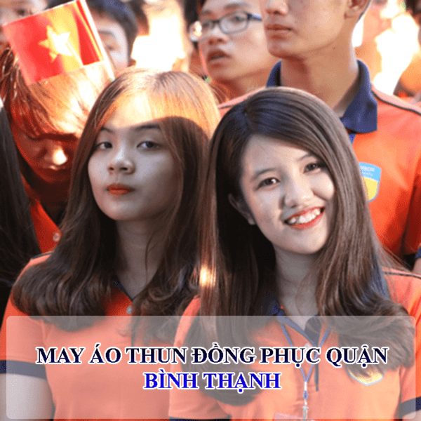 Hai nữ học sinh mặc áo thun đồng phục màu cam nhìn vào ống kính